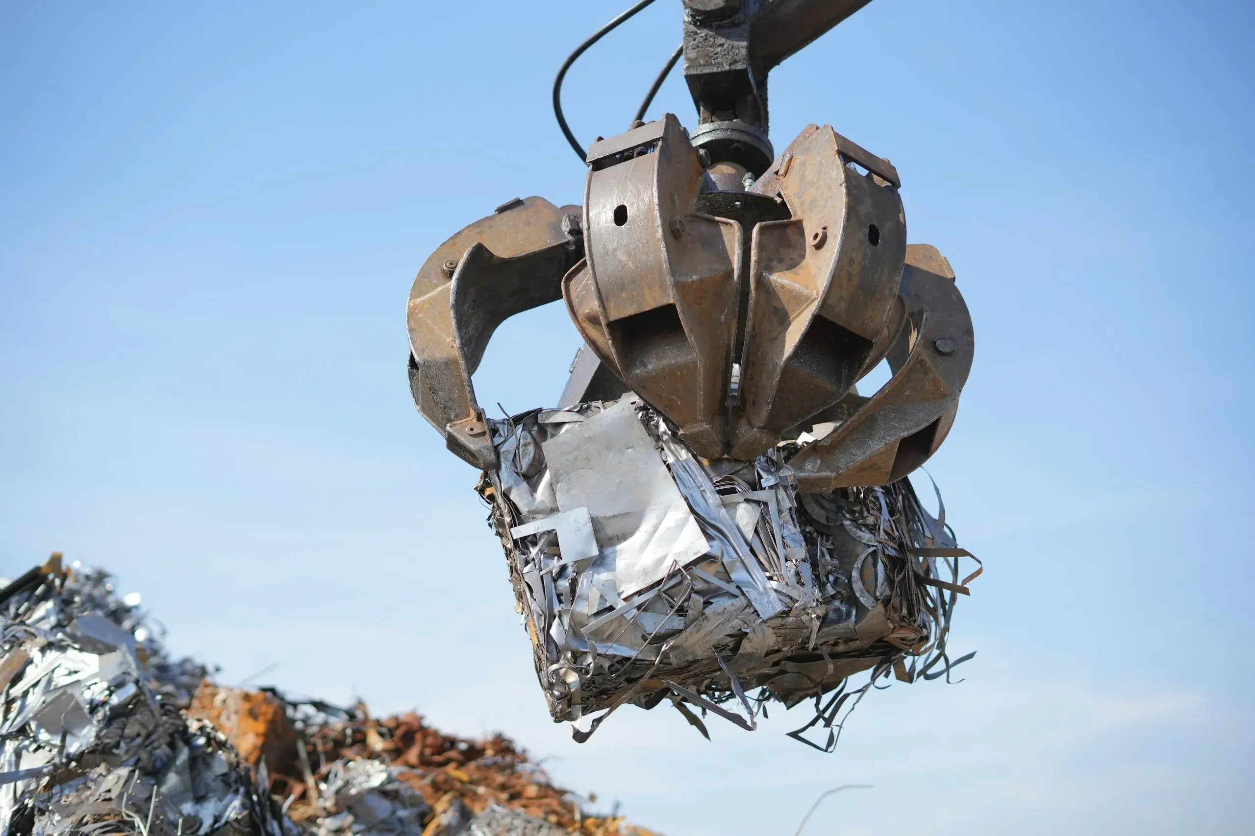 A grapple lifting a bale of scrap metal at a recycling yard